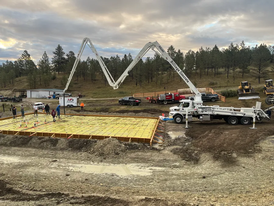 Concrete pump truck pouring a large shop slab on a rural Montana job site