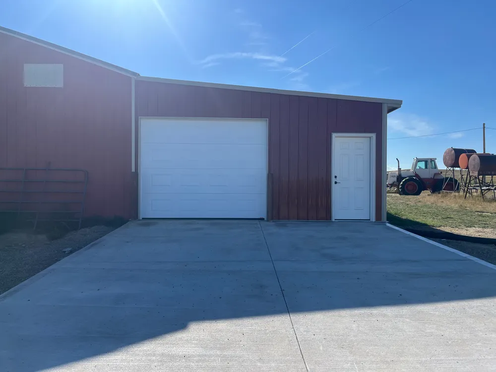 Finished red garage addition with a white overhead door and concrete apron
