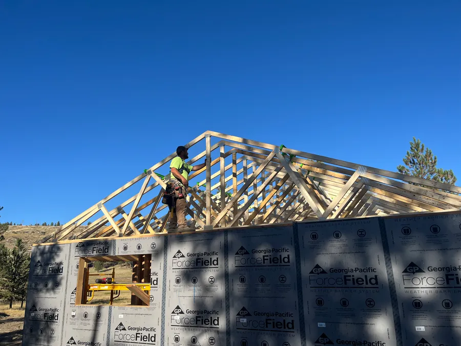 Hammer Down crew member setting roof trusses on a stick-framed build