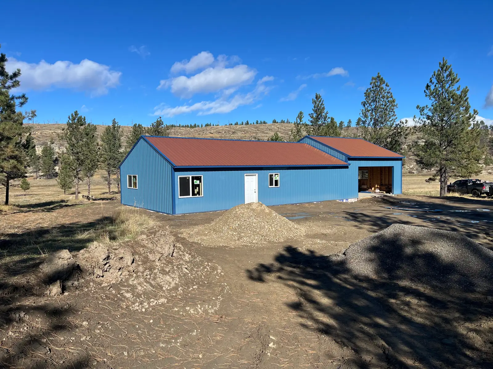 Completed blue custom home with a metal roof on a rural Montana property