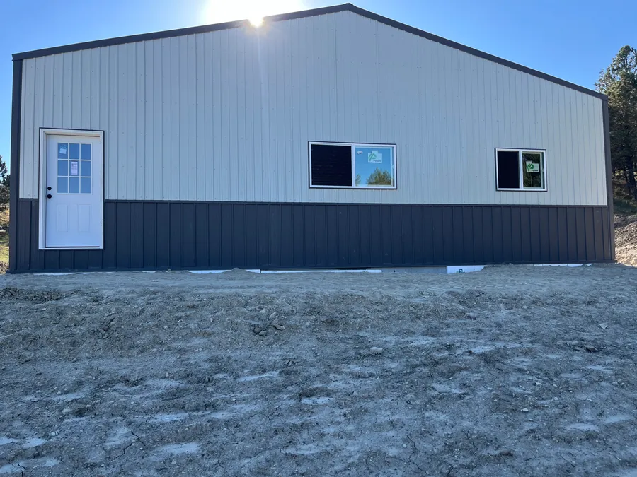Metal siding, walk door, and windows on the living side